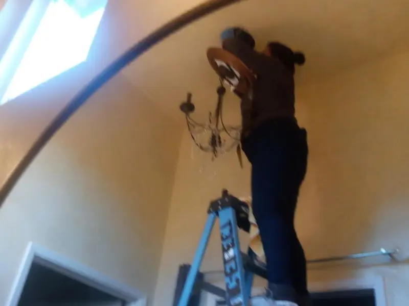 Electrician installing a chandelier in a Oildale residence